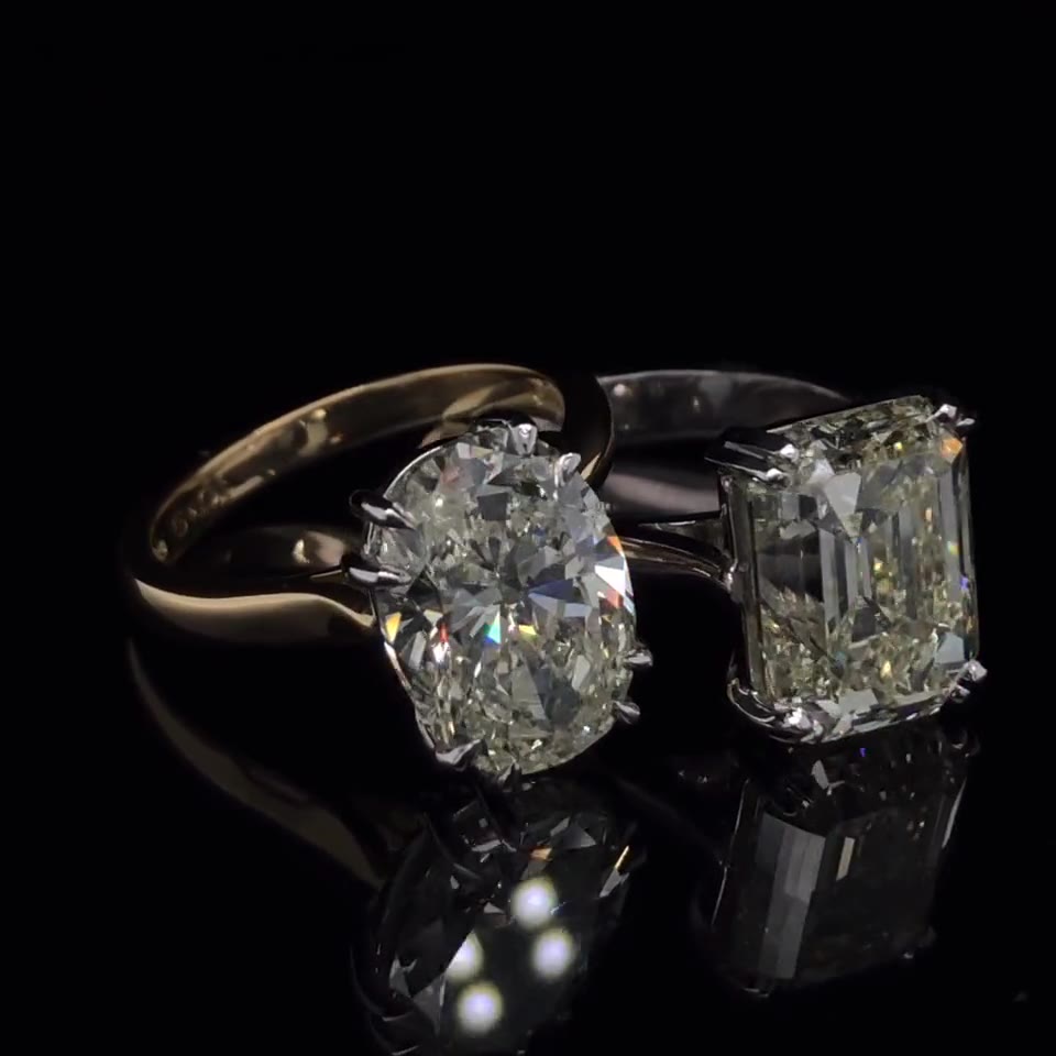 Anillos de compromiso con diamante oval y esmeralda sobre fondo negro
